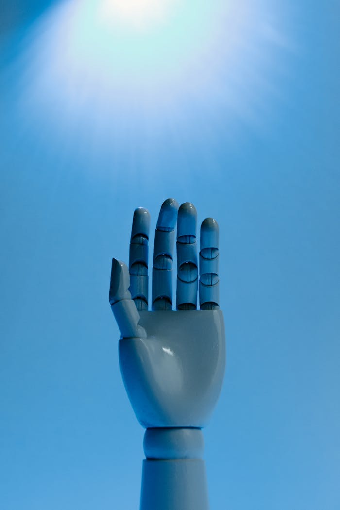 A robotic hand reaches up under a bright blue light, symbolizing future technology.